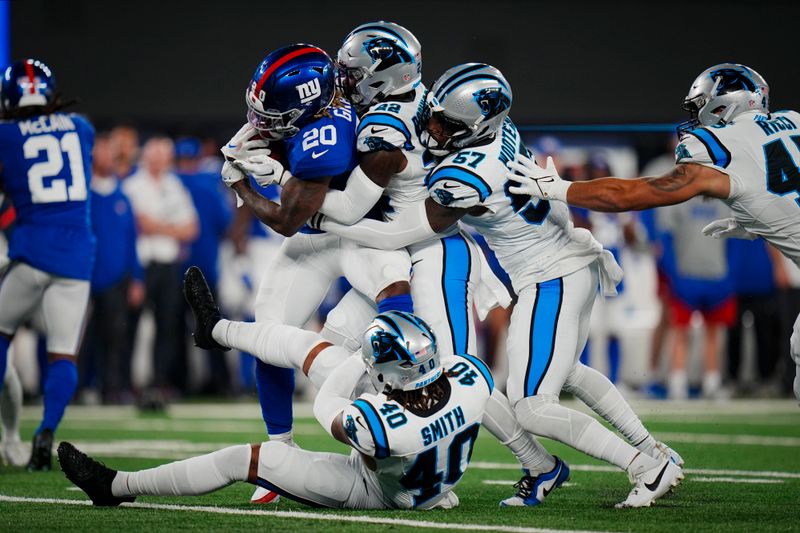 New York Giants running back Eric Gray (20) is tackled by Carolina Panthers safety Jammie Robinson, center, and linebackers Chandler Wooten, right, and Brandon Smith, bottom, during an NFL pre-season football game on Friday, Aug. 18, 2023, in East Rutherford, N.J. (AP Photo/Rusty Jones)