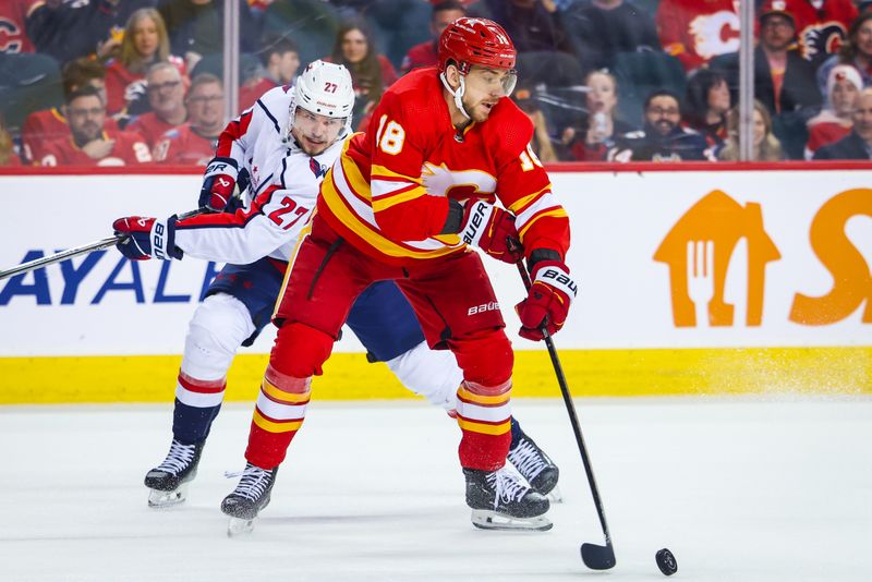 Mar 18, 2024; Calgary, Alberta, CAN; Calgary Flames left wing A.J. Greer (18) controls the puck against Washington Capitals defenseman Alexander Alexeyev (27) during the second period at Scotiabank Saddledome. Mandatory Credit: Sergei Belski-USA TODAY Sports