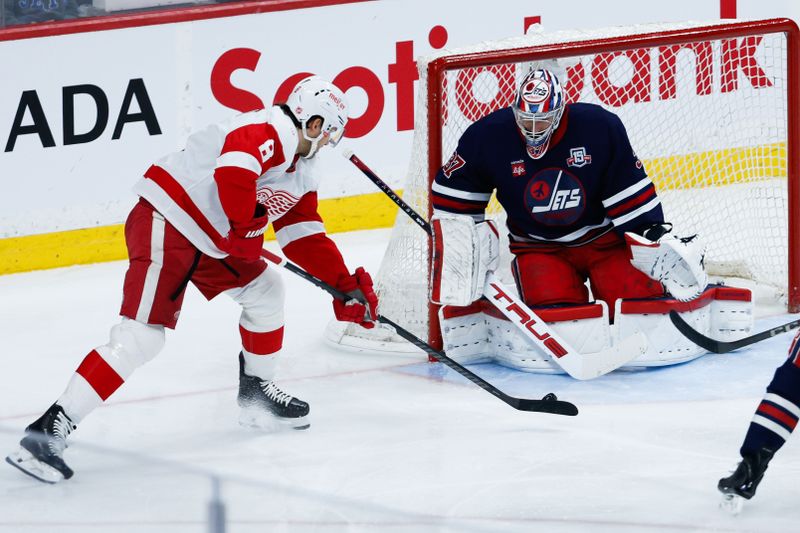 Jan 24, 2026; Winnipeg, Manitoba, CAN; Winnipeg Jets goalie Connor Hellebuyck (37) stops Detroit Red Wings defenseman Ben Chiarot (8) during the second period at Canada Life Centre. Mandatory Credit: Terrence Lee-Imagn Images