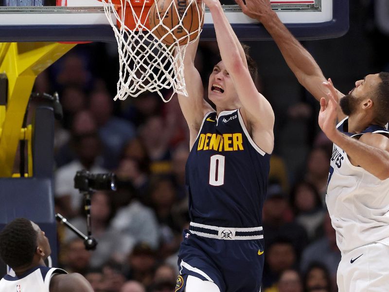 DENVER, COLORADO - APRIL 10: Christian Braun #0 of the Denver Nuggets dunks Rudy Gobert #27 of the Minnesota Timberwolves during the fourth quarter at Ball Arena on April 10, 2024 in Denver, Colorado. NOTE TO USER: User expressly acknowledges and agrees that, by downloading and or using this photograph, User is consenting to the terms and conditions of the Getty Images License Agreement.  (Photo by Matthew Stockman/Getty Images)