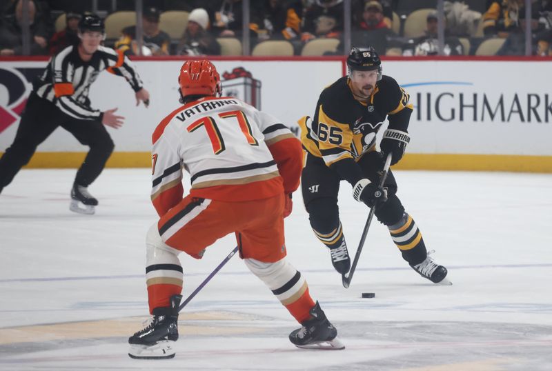 Dec 9, 2025; Pittsburgh, Pennsylvania, USA;  Pittsburgh Penguins defenseman Erik Karlsson (65) skates with the puck against Anaheim Ducks right wing Frank Vatrano (77) during the first period at PPG Paints Arena. Mandatory Credit: Charles LeClaire-Imagn Images
