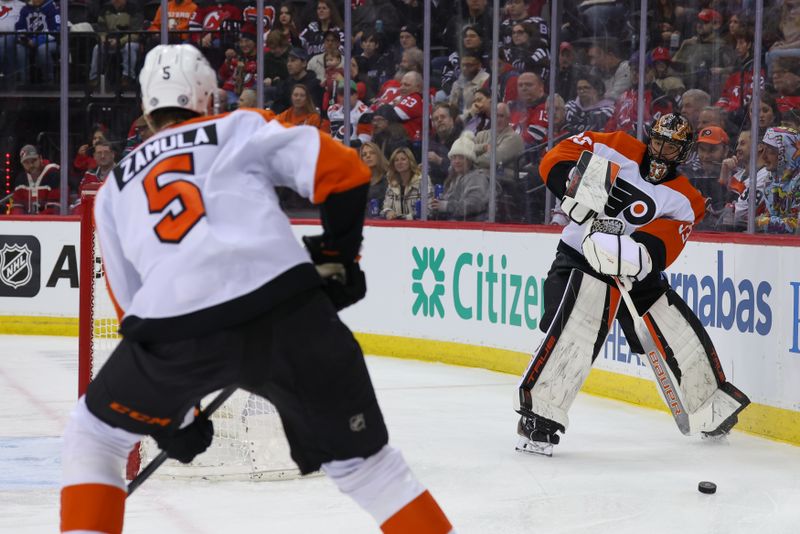 Jan 18, 2025; Newark, New Jersey, USA; Philadelphia Flyers goaltender Samuel Ersson (33) passes the puck to Philadelphia Flyers defenseman Egor Zamula (5) against the New Jersey Devils during the second period at Prudential Center. Mandatory Credit: Ed Mulholland-Imagn Images