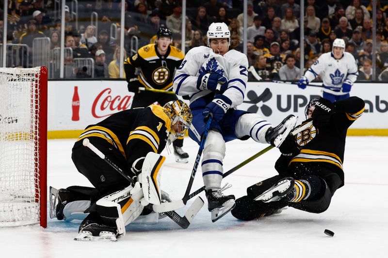 Oct 26, 2024; Boston, Massachusetts, USA; Toronto Maple Leafs left wing Matthew Knies (23) is upended by Boston Bruins right wing Justin Brazeau (55) battling for a rebound in front of goaltender Jeremy Swayman (1) during the second period at TD Garden. Mandatory Credit: Winslow Townson-Imagn Images