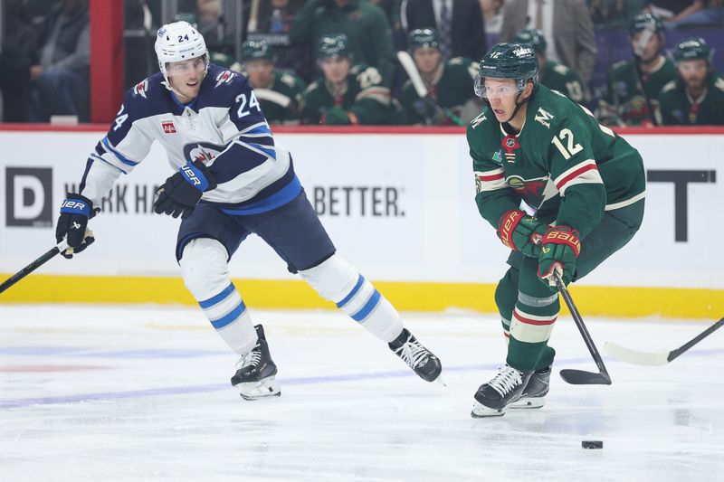 Sep 30, 2025; Saint Paul, Minnesota, USA; Minnesota Wild forward Matt Boldy (12) skates with the puck as Winnipeg Jets defenseman Haydn Fleury (24) defends during the first period at Grand Casino Arena. Mandatory Credit: Matt Krohn-Imagn Images