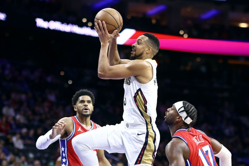 PHILADELPHIA, PENNSYLVANIA - MARCH 08: CJ McCollum #3 of the New Orleans Pelicans drives to the basket between Tobias Harris #12 and Buddy Hield #17 of the Philadelphia 76ers during the first quarter at the Wells Fargo Center on March 08, 2024 in Philadelphia, Pennsylvania. NOTE TO USER: User expressly acknowledges and agrees that, by downloading and or using this photograph, User is consenting to the terms and conditions of the Getty Images License Agreement.  (Photo by Tim Nwachukwu/Getty Images)