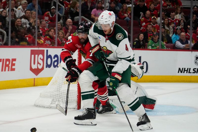 Oct 4, 2024; Chicago, Illinois, USA;Chicago Blackhawks left wing Patrick Maroon (77) and Minnesota Wild defenseman Jon Merrill (4) go for the puck during the third period at United Center. Mandatory Credit: David Banks-Imagn Images