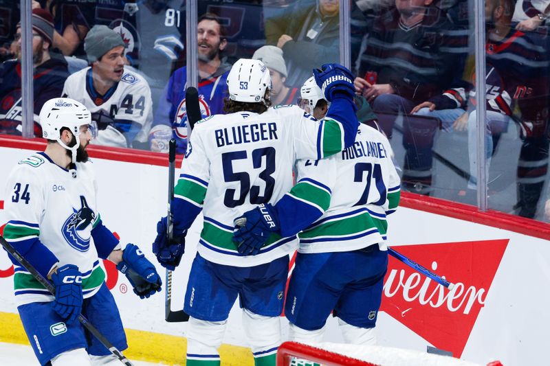 Jan 14, 2025; Winnipeg, Manitoba, CAN;  Vancouver Canucks forward Nils Hoglander (21) celebrates with forward Teddy Blueger (53) after scoring a goal against the Winnipeg Jets during the third period at Canada Life Centre. Mandatory Credit: Terrence Lee-Imagn Images