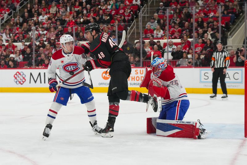 Jan 1, 2026; Raleigh, North Carolina, USA;  Carolina Hurricanes left wing Jordan Martinook (48) gets hit by the shot in front of Montréal Canadiens goaltender Jakub Dobes (75) and defenseman Lane Hutson (48) during the first period at Lenovo Center. Mandatory Credit: James Guillory-Imagn Images