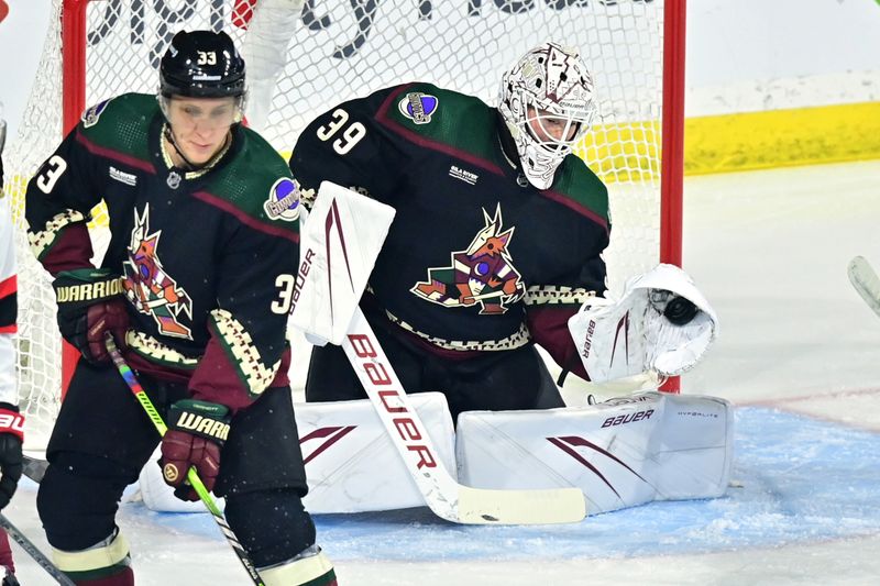 Dec 19, 2023; Tempe, Arizona, USA; Arizona Coyotes goaltender Connor Ingram (39) makes a glove save as defenseman Travis Dermott (33) defends in the first period against the Ottawa Senators at Mullett Arena. Mandatory Credit: Matt Kartozian-USA TODAY Sports