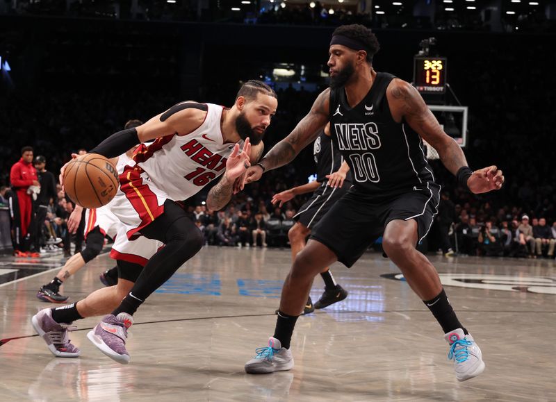 NEW YORK, NEW YORK - JANUARY 15:  Caleb Martin #16 of the Miami Heat drives against Royce O'Neale #00 of the Brooklyn Nets during their game at Barclays Center on January 15, 2024 in New York City.   User expressly acknowledges and agrees that, by downloading and or using this photograph, User is consenting to the terms and conditions of the Getty Images License Agreement.  (Photo by Al Bello/Getty Images)