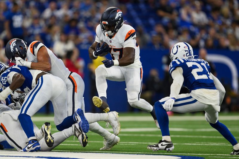 Denver Broncos running back Audric Estime (37) jumps through a hole in the line against Indianapolis Colts cornerback Dallis Flowers (21) during an NFL football game, Sunday, Aug. 11, 2024, in Indianapolis. (AP Photo/Zach Bolinger)