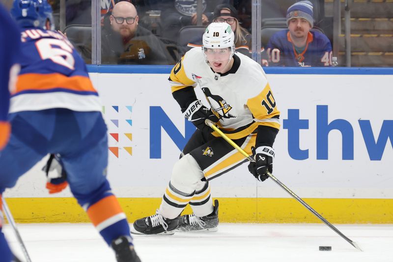 Nov 5, 2024; Elmont, New York, USA; Pittsburgh Penguins left wing Drew O'Connor (10) skates with the puck against New York Islanders defenseman Ryan Pulock (6) during the first period at UBS Arena. Mandatory Credit: Brad Penner-Imagn Images