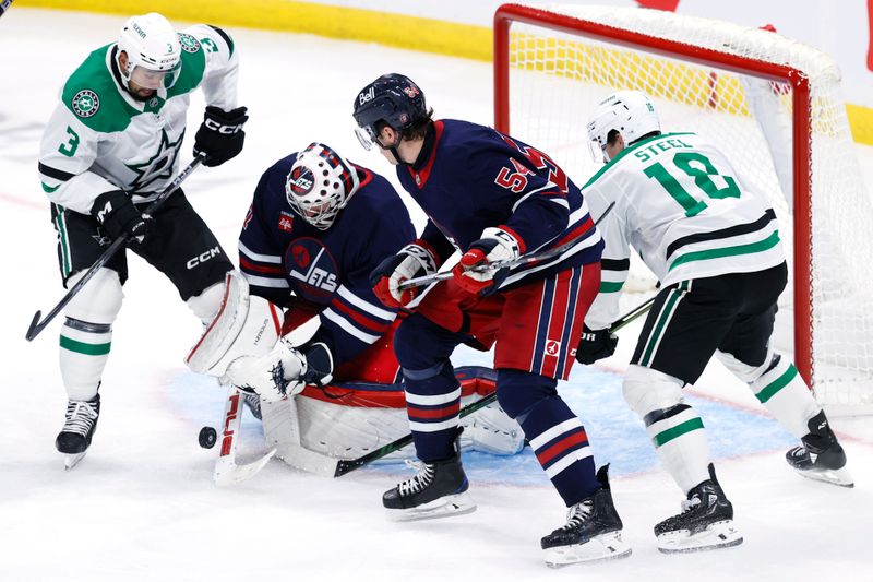 Nov 9, 2024; Winnipeg, Manitoba, CAN; Winnipeg Jets goaltender Connor Hellebuyck (37) blocks a shot as Dallas Stars defenseman Mathew Dumba (3) and Winnipeg defenseman Dylan Samberg (54) looking for a rebound in the third period at Canada Life Centre. Mandatory Credit: James Carey Lauder-Imagn Images