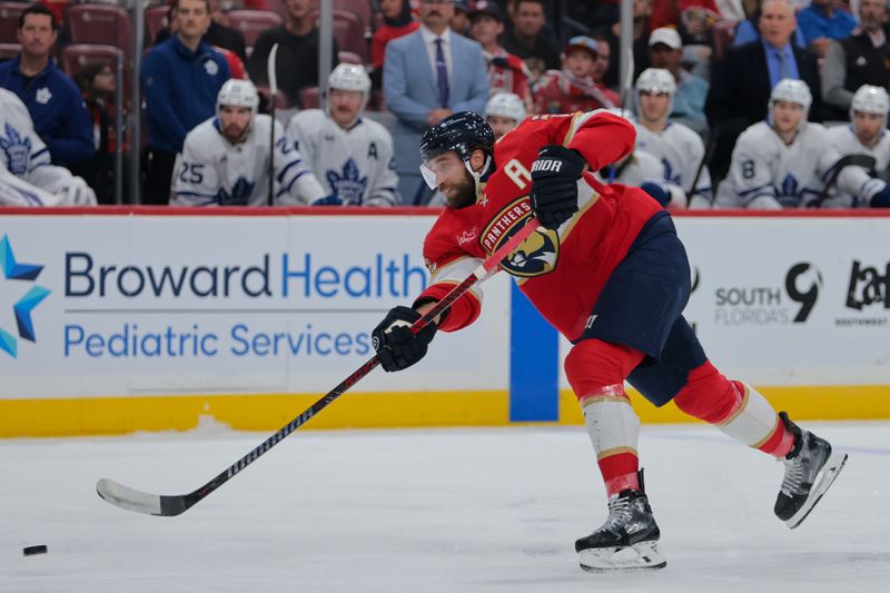 Nov 27, 2024; Sunrise, Florida, USA; Florida Panthers defenseman Aaron Ekblad (5) shoots the puck against the Toronto Maple Leafs during the first period at Amerant Bank Arena. Mandatory Credit: Sam Navarro-Imagn Images