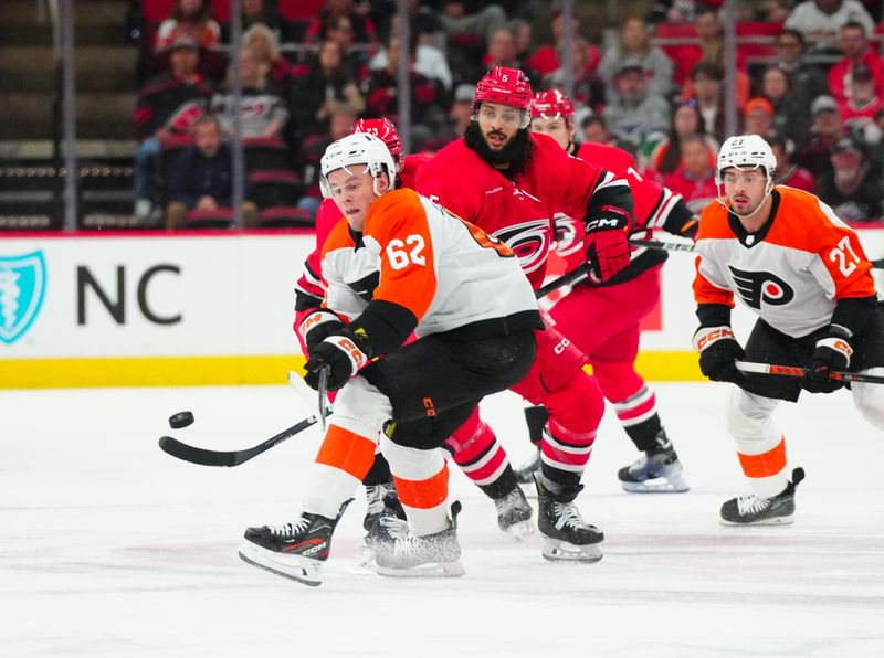 Mar 21, 2024; Raleigh, North Carolina, USA; Philadelphia Flyers right wing Olle Lycksell (62) and Carolina Hurricanes defenseman Jalen Chatfield (5) watch the puck during the first period at PNC Arena. Mandatory Credit: James Guillory-USA TODAY Sports