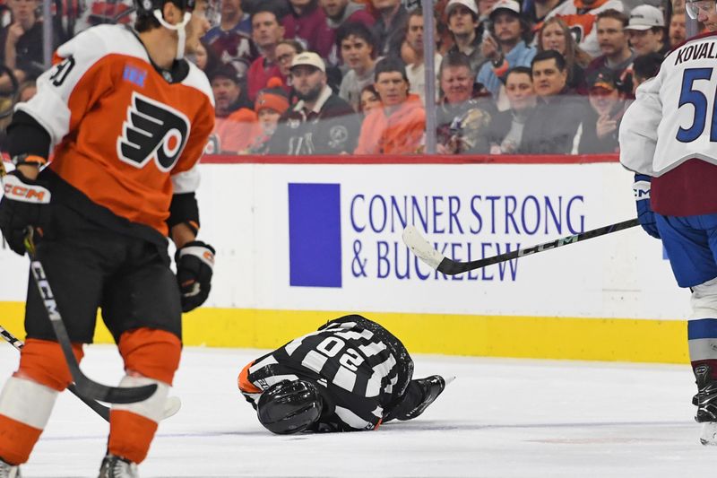 Nov 18, 2024; Philadelphia, Pennsylvania, USA; Referee Barry Anderson (20) lays on the ice after colliding with a player during game between Philadelphia Flyers and Colorado Avalanche in the first period at Wells Fargo Center. Mandatory Credit: Eric Hartline-Imagn Images