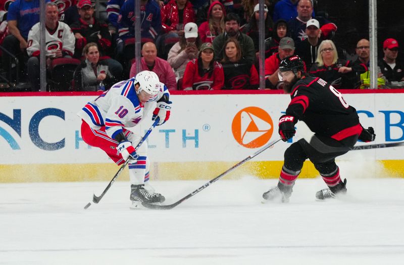 Mar 12, 2024; Raleigh, North Carolina, USA; Carolina Hurricanes defenseman Brent Burns (8) pokes the puck away from New York Rangers left wing Artemi Panarin (10) during the first period at PNC Arena. Mandatory Credit: James Guillory-USA TODAY Sports