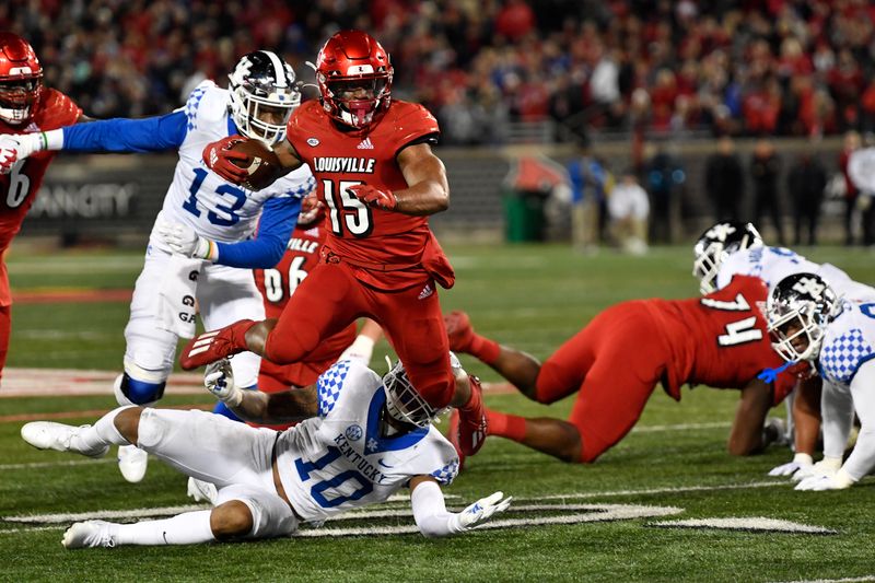 Nov 27, 2021; Louisville, Kentucky, USA;  Louisville Cardinals running back Jalen Mitchell (15) leaps to avoid the tackle of Kentucky Wildcats linebacker Jacquez Jones (10) during the first quarter at Cardinal Stadium. Mandatory Credit: Jamie Rhodes-USA TODAY Sports