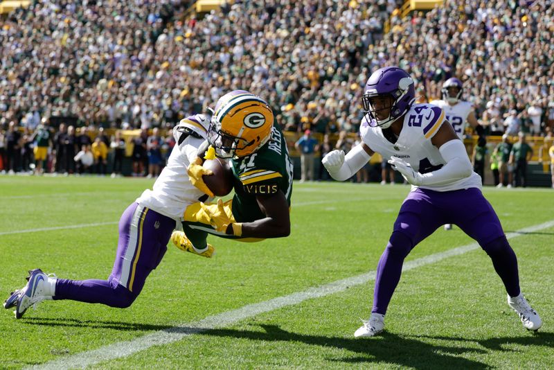 Green Bay Packers wide receiver Jayden Reed (11) catches a touchdown pass over Minnesota Vikings cornerback Byron Murphy Jr., left and safety Camryn Bynum (24) during the first half of an NFL football game Sunday, Sept. 29, 2024, in Green Bay, Wis. (AP Photo/Matt Ludtke)