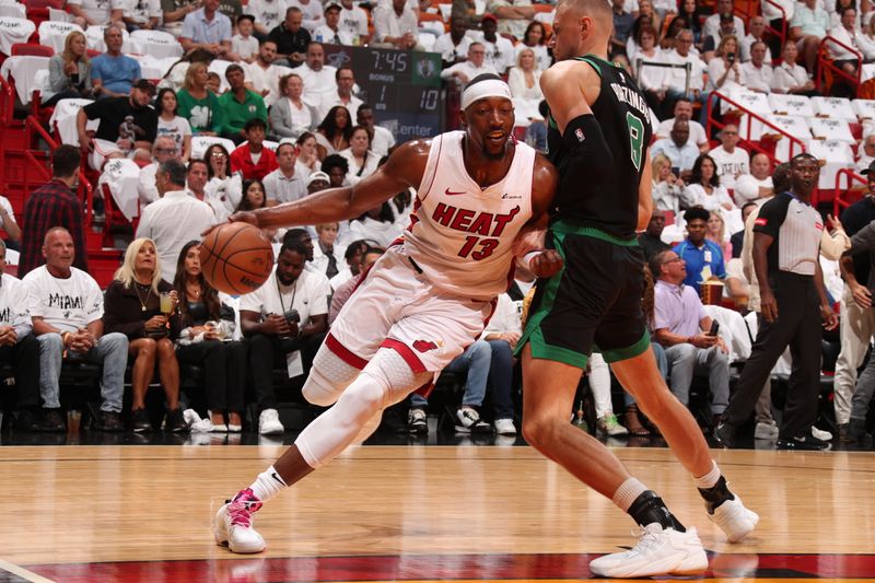 MIAMI, FL - APRIL 27: Bam Adebayo #13 of the Miami Heat drives to the basket against Kristaps Porzingis #8 of the Boston Celtics during the game during Round 1 Game 3 of the 2024 NBA Playoffs on April 27, 2024 at Kaseya Center in Miami, Florida. NOTE TO USER: User expressly acknowledges and agrees that, by downloading and or using this Photograph, user is consenting to the terms and conditions of the Getty Images License Agreement. Mandatory Copyright Notice: Copyright 2024 NBAE (Photo by Issac Baldizon/NBAE via Getty Images)