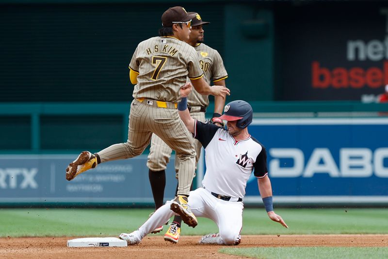 Jul 25, 2024; Washington, District of Columbia, USA; San Diego Padres shortstop Ha-Seong Kim (7) leaps after turning a double play at second base ahead of a slide by Washington Nationals outfielder Lane Thomas (28) during the fourth inning at Nationals Park. Mandatory Credit: Geoff Burke-USA TODAY Sports