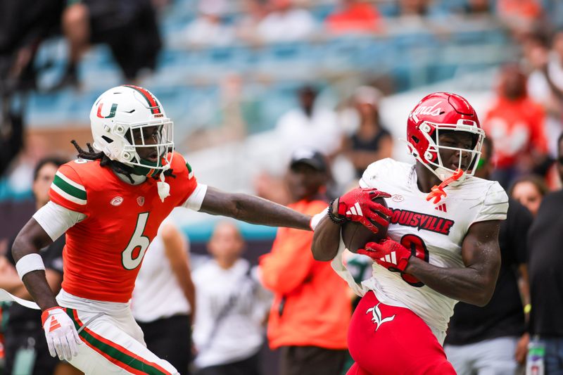 Nov 18, 2023; Miami Gardens, Florida, USA; Louisville Cardinals wide receiver Chris Bell (0) catches the football against Miami Hurricanes defensive back Damari Brown (6) during the second quarter at Hard Rock Stadium. Mandatory Credit: Sam Navarro-USA TODAY Sports