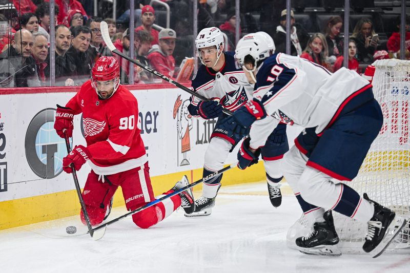 Feb 27, 2025; Detroit, Michigan, USA; Detroit Red Wings center Joe Veleno (90) clears the puck past Columbus Blue Jackets defenseman Damon Severson (78) and left wing Dmitri Voronkov (10) during the first period at Little Caesars Arena. Mandatory Credit: Tim Fuller-Imagn Images