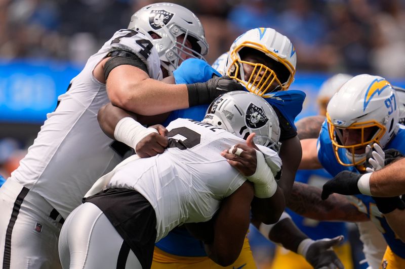 Los Angeles Chargers defensive tackle Otito Ogbonnia, top middle, tackles Las Vegas Raiders running back Zamir White, bottom, as offensive tackle Kolton Miller (74) tries to block during the first half of an NFL football game, Sunday, Sept. 8, 2024, in Inglewood, Calif. (AP Photo/Marcio Jose Sanchez)