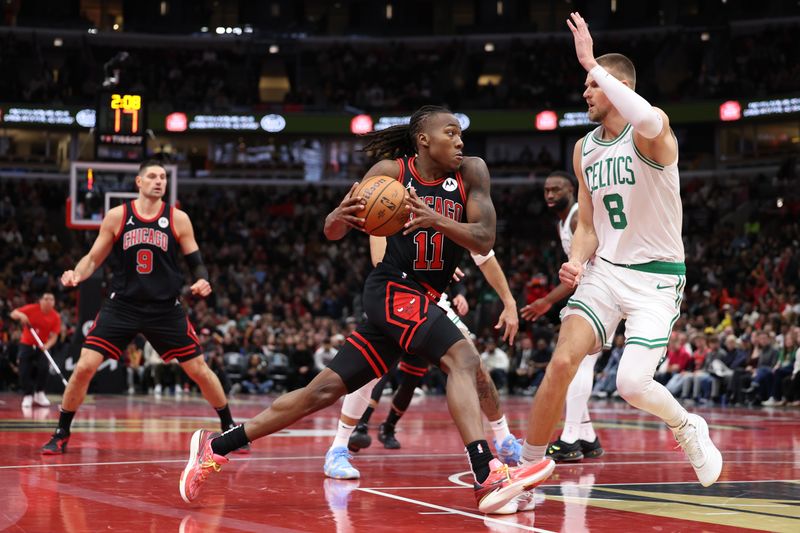 CHICAGO, ILLINOIS - NOVEMBER 29: Ayo Dosunmu #11 of the Chicago Bulls drives to the basket against Kristaps Porzingis #8 of the Boston Celtics during the fourth quarter of the Emirates NBA Cup game at the United Center on November 29, 2024 in Chicago, Illinois. NOTE TO USER: User expressly acknowledges and agrees that, by downloading and or using this photograph, User is consenting to the terms and conditions of the Getty Images License Agreement.  (Photo by Luke Hales/Getty Images)