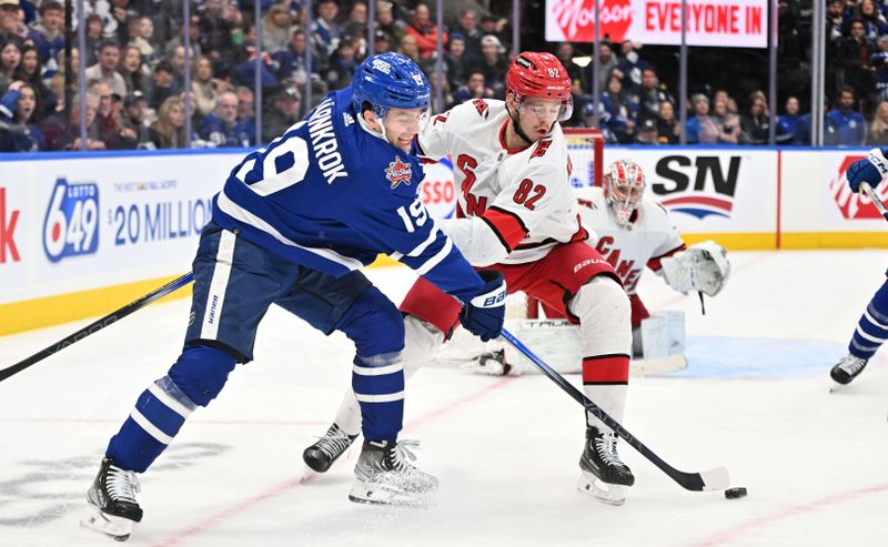 Dec 30, 2023; Toronto, Ontario, CAN; Toronto Maple Leafs forward Calle Jarnkrok (19) tries to pass the puck as Carolina Hurricanes forward Jesperi Kotkaniemi (82) defends in the third period at Scotiabank Arena. Mandatory Credit: Dan Hamilton-USA TODAY Sports