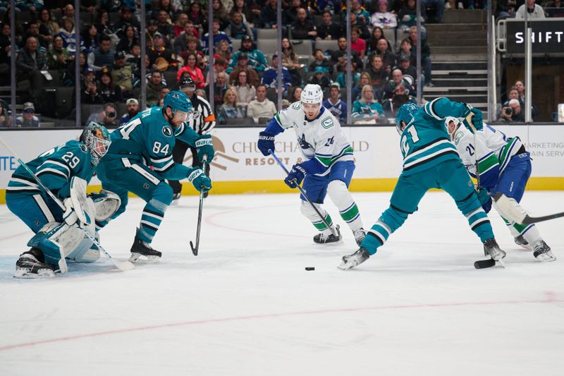 Nov 2, 2024; San Jose, California, USA; Vancouver Canucks center Pius Suter (24) plays the puck against San Jose Sharks defenseman Jan Rutta (84), goaltender Mackenzie Blackwood (29) and center Alex Wennberg (21)during the first period at SAP Center at San Jose. Mandatory Credit: Robert Edwards-Imagn Images