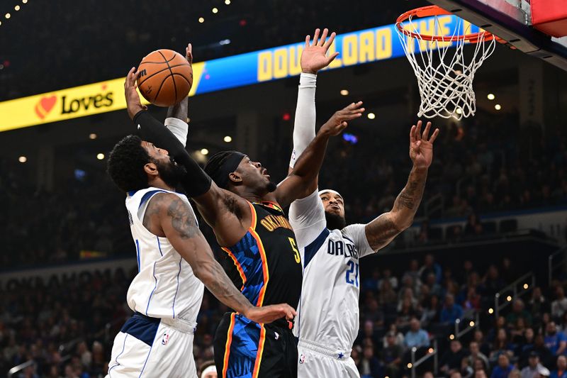 OKLAHOMA CITY, OKLAHOMA - NOVEMBER 17: Luguentz Dort #5 of the Oklahoma City Thunder attempts a shot at the rim while being defended by Kyrie Irving #11 and Daniel Gafford #21 of the Dallas Mavericks during the first half at Paycom Center on November 17, 2024 in Oklahoma City, Oklahoma. NOTE TO USER: User expressly acknowledges and agrees that, by downloading and or using this photograph, User is consenting to the terms and conditions of the Getty Images License Agreement. (Photo by Joshua Gateley/Getty Images)