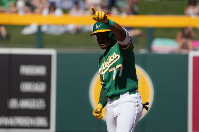 Mar 8, 2026; Mesa, Arizona, USA; Athletics third baseman Andy Ibáñez (77) hits a double against the Los Angeles Dodgers in the first inning at Hohokam Stadium. Mandatory Credit: Rick Scuteri-Imagn Images