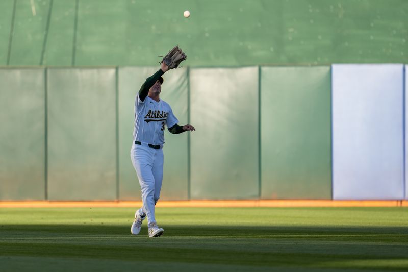 Aug 20, 2024; Oakland, California, USA; Oakland Athletics center fielder JJ Bleday (33) fields a fly ball against the Tampa Bay Rays during the first inning at Oakland-Alameda County Coliseum. Mandatory Credit: Neville E. Guard-USA TODAY Sports