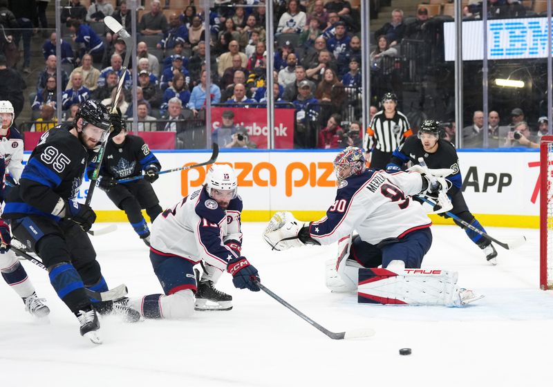 Jan 22, 2025; Toronto, Ontario, CAN; Toronto Maple Leafs defenseman Oliver Ekman-Larsson (95) battles for the puck with Columbus Blue Jackets defenseman Dante Fabbro (15) in front of goaltender Elvis Merzlikins (90) during the third period at Scotiabank Arena. Mandatory Credit: Nick Turchiaro-Imagn Images
