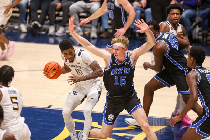 Feb 11, 2025; Morgantown, West Virginia, USA; West Virginia Mountaineers guard Sencire Harris (10) drives against Brigham Young Cougars forward Richie Saunders (15) during the second half at WVU Coliseum. Mandatory Credit: Ben Queen-Imagn Images