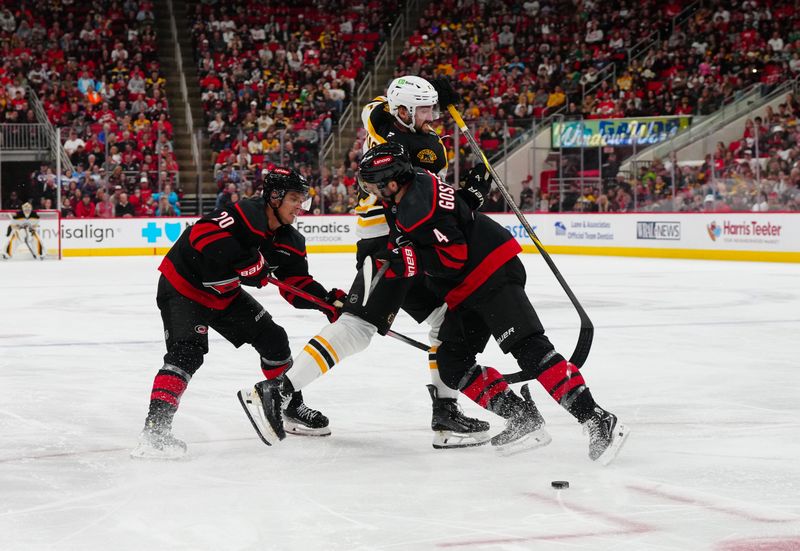 Oct 31, 2024; Raleigh, North Carolina, USA;  Carolina Hurricanes defenseman Shayne Gostisbehere (4) goes to check Boston Bruins center Mark Kastelic (47) during the second period at Lenovo Center. Mandatory Credit: James Guillory-Imagn Images