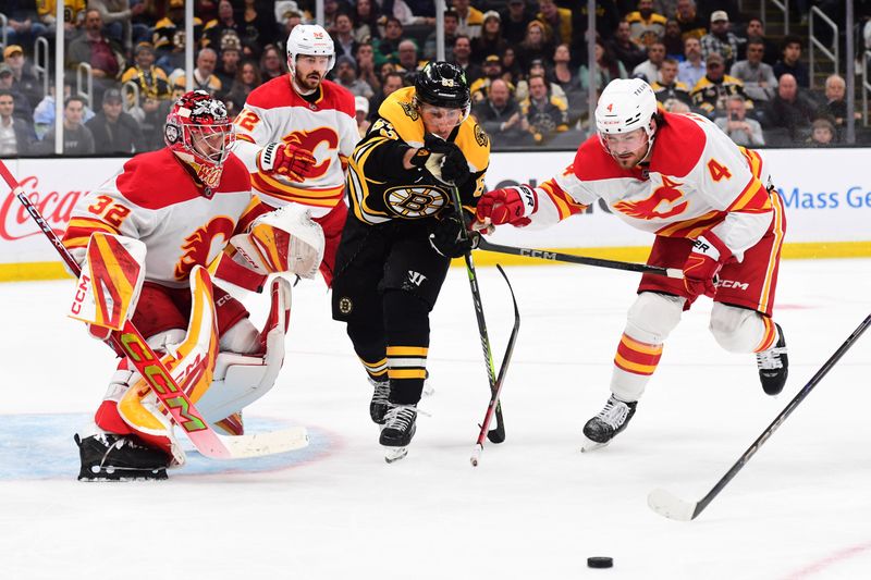 Nov 7, 2024; Boston, Massachusetts, USA;  Boston Bruins left wing Brad Marchand (63) and Calgary Flames defenseman Rasmus Andersson (4) battle for a loose puck in front of goaltender Dustin Wolf (32) during the third period at TD Garden. Mandatory Credit: Bob DeChiara-Imagn Images