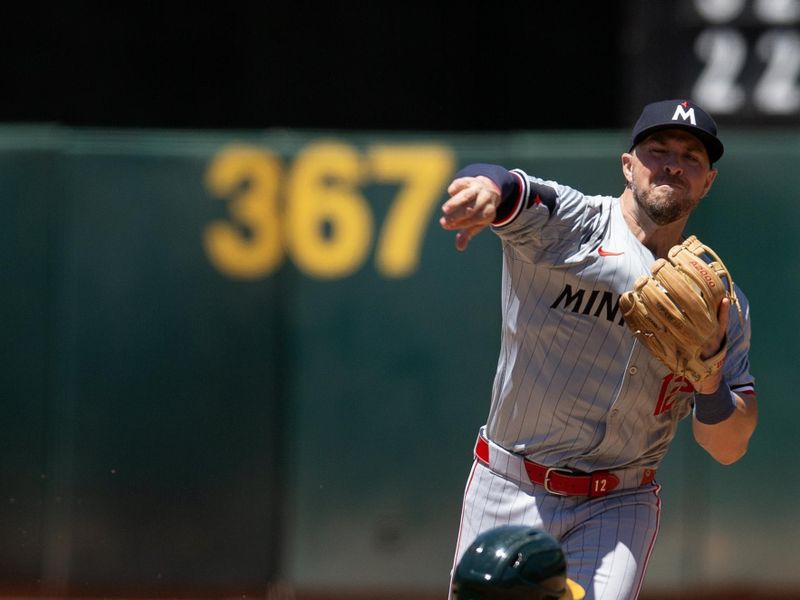 Jun 22, 2024; Oakland, California, USA; Minnesota Twins second baseman Kyle Farmer (12) throws over Oakland Athletics catcher Kyle McCann (52) to complete a double play during the third inning at Oakland-Alameda County Coliseum. Mandatory Credit: D. Ross Cameron-USA TODAY Sports