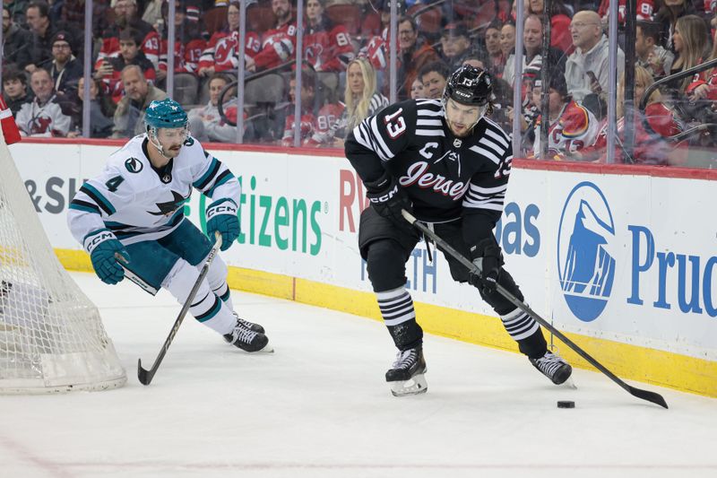 Dec 1, 2023; Newark, New Jersey, USA; New Jersey Devils center Nico Hischier (13) skates with the puck as San Jose Sharks defenseman Kyle Burroughs (4) pursues during the first period at Prudential Center. Mandatory Credit: Vincent Carchietta-USA TODAY Sports