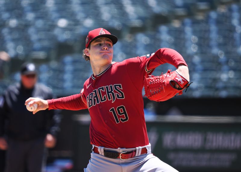 May 17, 2023; Oakland, California, USA; Arizona Diamondbacks starting pitcher Ryne Nelson (19) pitches the ball against the Oakland Athletics during the first inning at Oakland-Alameda County Coliseum. Mandatory Credit: Kelley L Cox-USA TODAY Sports