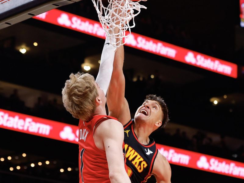 ATLANTA, GEORGIA - FEBRUARY 23: Bogdan Bogdanovic #13 of the Atlanta Hawks goes up for a shot against Gradey Dick #1 of the Toronto Raptors during the first quarter at State Farm Arena on February 23, 2024 in Atlanta, Georgia. NOTE TO USER: User expressly acknowledges and agrees that, by downloading and or using this photograph, User is consenting to the terms and conditions of the Getty Images License Agreement. (Photo by Todd Kirkland/Getty Images)