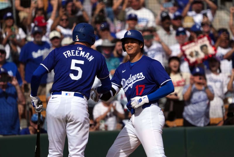 Feb 27, 2024; Phoenix, Arizona, USA; Los Angeles Dodgers designated hitter Shohei Ohtani (17) slaps hands with first baseman Freddie Freeman (5) after hitting a two run home run during the fifth inning against the Chicago White Sox at Camelback Ranch-Glendale. Mandatory Credit: Joe Camporeale-USA TODAY Sports