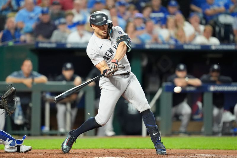 Oct 9, 2024; Kansas City, Missouri, USA; New York Yankees designated hitter Giancarlo Stanton (27) hits an RBI-double in the fourth inning against the Kansas City Royals  during game three of the NLDS for the 2024 MLB Playoffs at Kauffman Stadium. Mandatory Credit: Jay Biggerstaff -Imagn Images