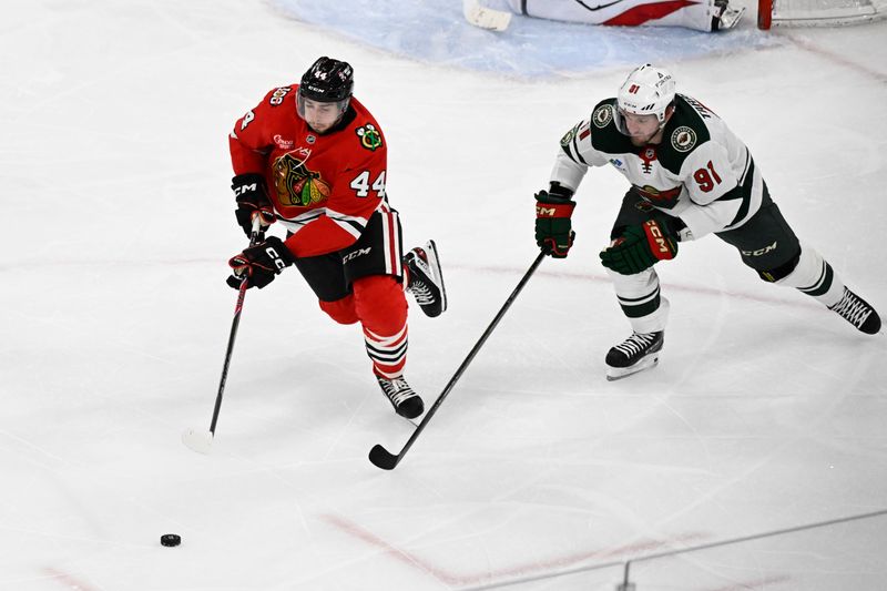 Mar 17, 2026; Chicago, Illinois, USA;  Chicago Blackhawks defenseman Wyatt Kaiser (44) and Minnesota Wild right wing Vladimir Tarasenko (91) chase the puck during the third period at United Center. Mandatory Credit: Matt Marton-Imagn Images