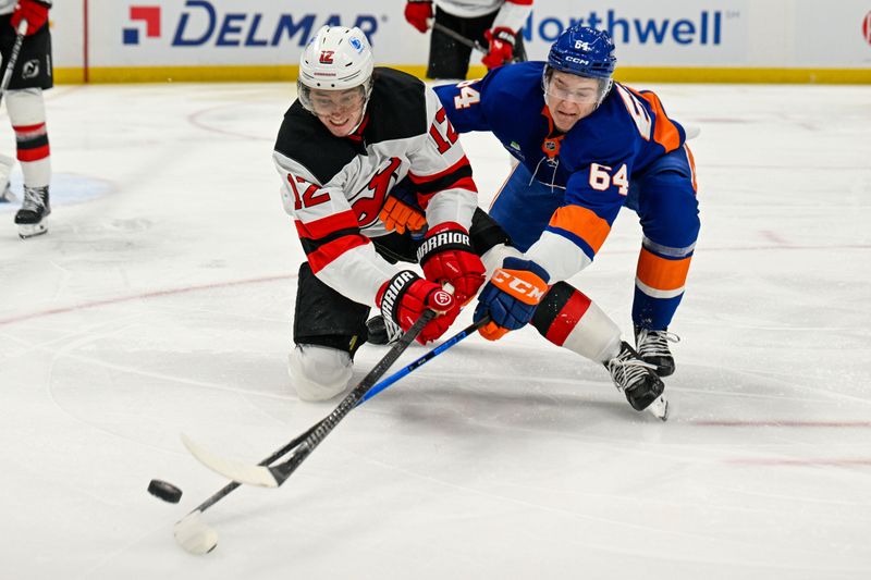 Jan 6, 2026; Elmont, New York, USA;  New York Islanders center Calum Ritchie (64) and New Jersey Devils center Cody Glass (12) battle for the puck during the second period at UBS Arena. Mandatory Credit: Dennis Schneidler-Imagn Images