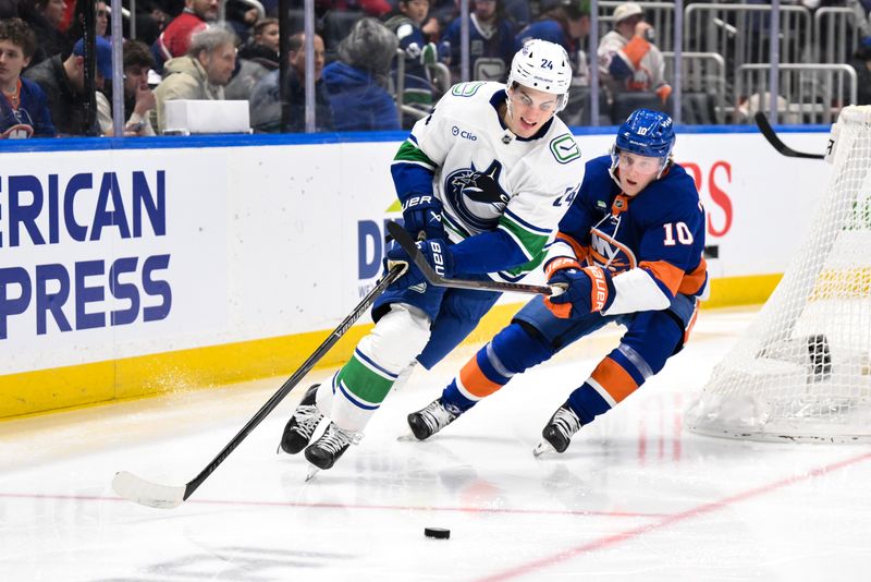 Dec 19, 2025; Elmont, New York, USA; Vancouver Canucks defenseman Zeev Buium (24) skates with the puck while defended by New York Islanders right wing Simon Holmstrom (10) during the second period at UBS Arena. Mandatory Credit: John Jones-Imagn Images