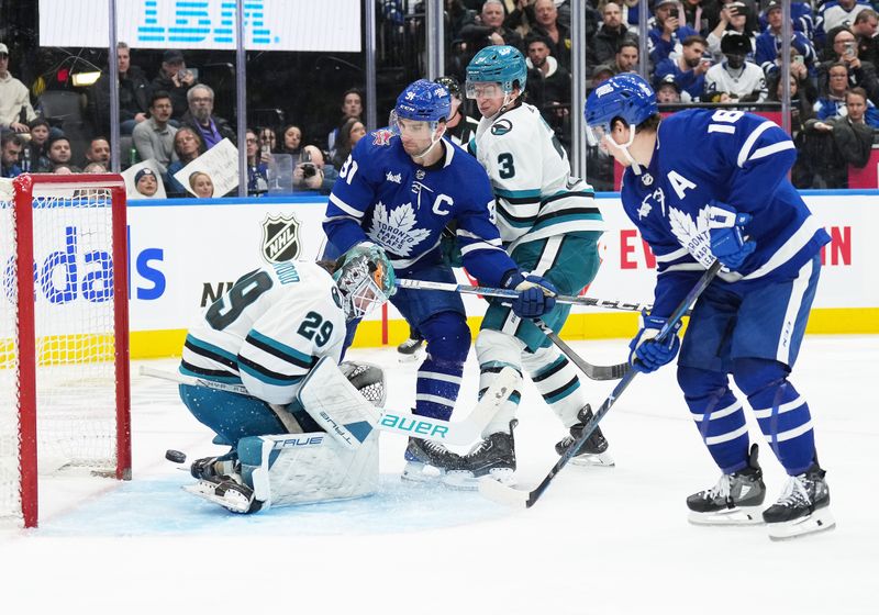 Jan 9, 2024; Toronto, Ontario, CAN; Toronto Maple Leafs center John Tavares (91) battles with San Jose Sharks defenseman Henry Thrun (3) as the puck goes past goaltender Mackenzie Blackwood (29) for a goal by Toronto Maple Leafs right wing Mitchell Marner (16) during the third period at Scotiabank Arena. Mandatory Credit: Nick Turchiaro-USA TODAY Sports