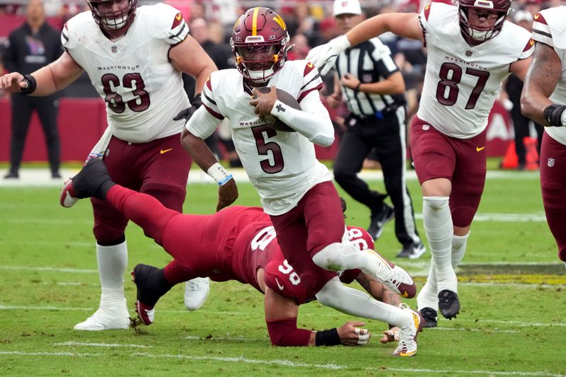 Washington Commanders quarterback Jayden Daniels (5) escapes the tackle of Arizona Cardinals defensive tackle Roy Lopez (98) during the first half of an NFL football game, Sunday, Sept. 29, 2024, in Glendale, Ariz. (AP Photo/Rick Scuteri)