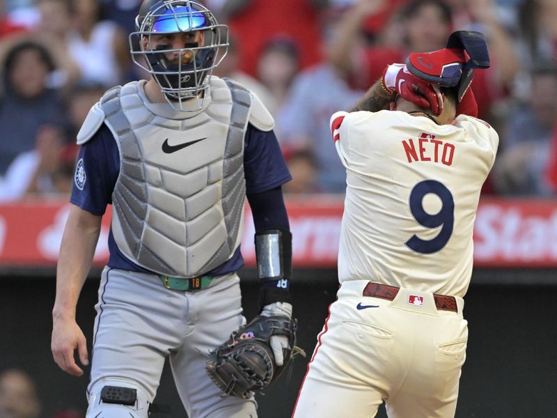 Jul 13, 2024; Anaheim, California, USA;  Cal Raleigh #29 of the Seattle Mariners looks on as Zach Neto #9 of the Los Angeles Angels covers his head as he scores a run on a single by Jo Adell #7 in the second inning at Angel Stadium. Mandatory Credit: Jayne Kamin-Oncea-USA TODAY Sports